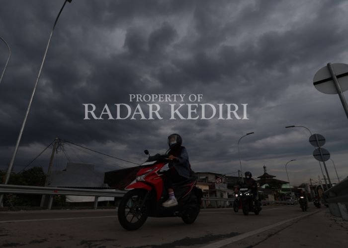 AWAN GELAP: Pengendara bermotor melintas di jalan di Desa Jongbiru yang sedang mendung.
