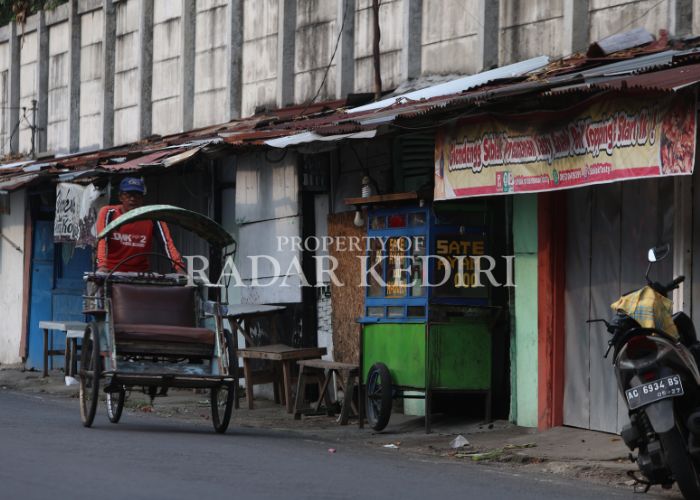 BAKAL DITERTIBKAN: Seorang tukang becak melintas di depan PKL yang berada di Jalan Patiunus, Kota Kediri.