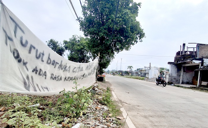 Warga memasang banner protes di jalan Desa Tiron, Banyakan yang terdampak Tol Ki Agung.