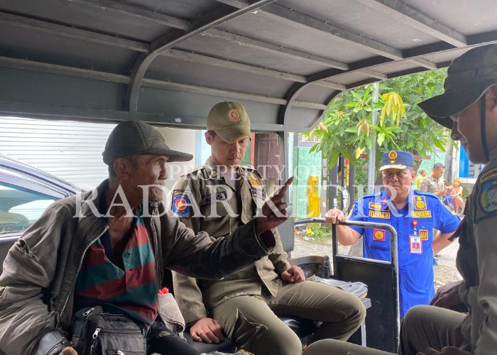 TERJARING RAZIA: Seorang gepeng menunjuk petugas Satpol PP saat diangkut ke dalam truk.