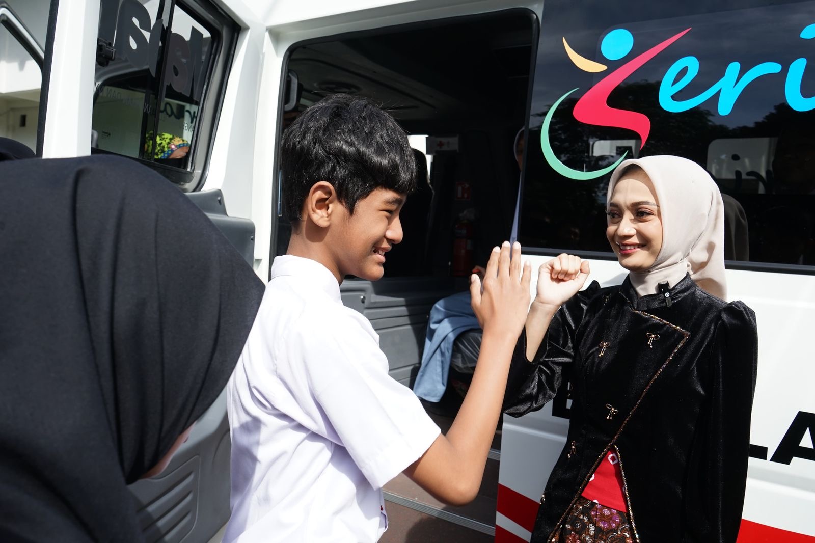 Siswa disabilitas berkomunikasi dengan Mbak Vinanda menggunakan bahasa isyarat. Anak-anak menyambut gembira bus sekolah khusus untuk mereka.