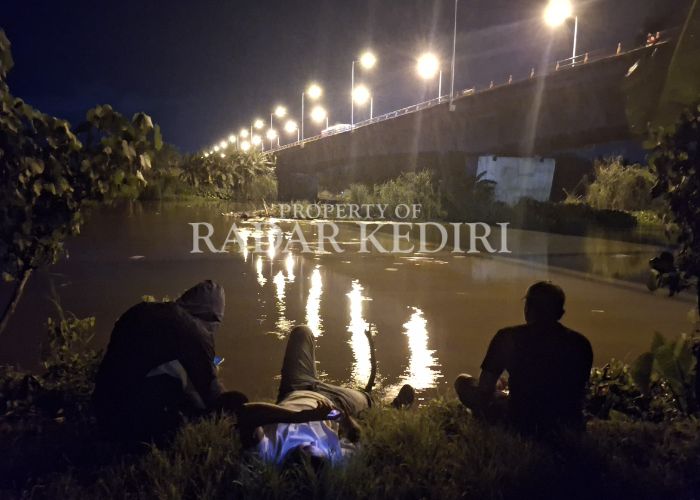 MENANTI PLADU: Warga bermain gawai di tepi Sungai Brantas di bawah Jembatan Semampir.