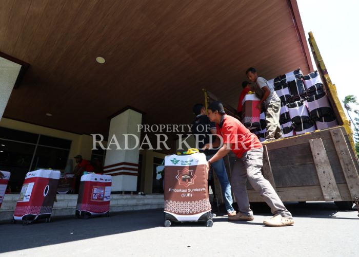 SIAP BERANGKAT: Petugas menurunkan koper haji di Pemkab Kediri.