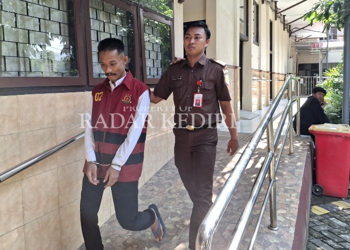 SIDANG PERDANA: Terdakwa Yusa dijaga petugas kejaksaan saar hendak menjalani persidangan di Pengadilan Negeri Kabupaten Kediri.