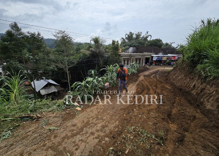 BENCANA ALAM: Warga melintas di jalan yang tertutup oleh material longsor di Kecamatan Mojo.