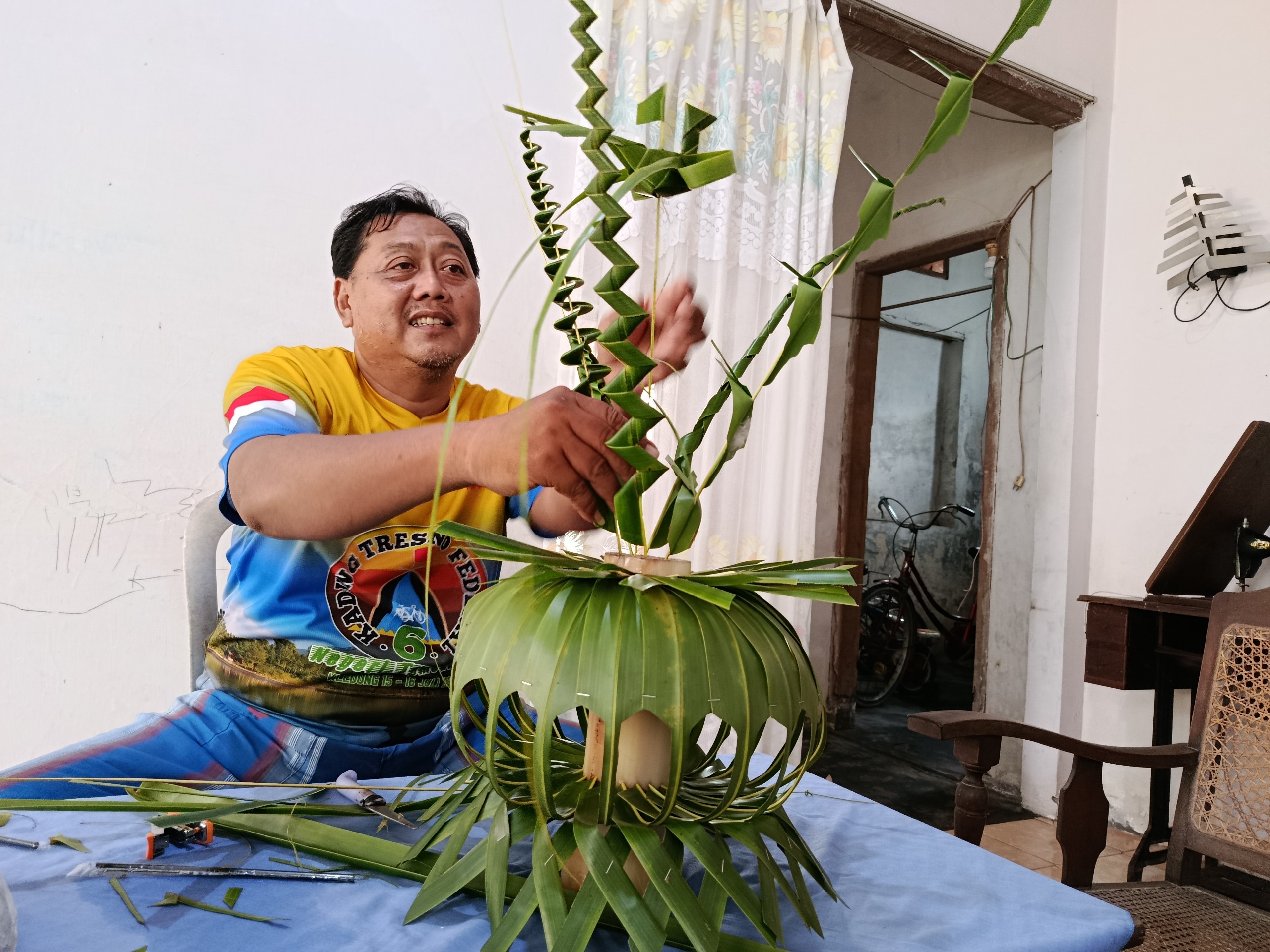 Suroso sedang membuat isen-isen kembar mayang di rumahnya, di Kelurahan Bujel, Kecamatan Mojoroto, Kota Kediri.