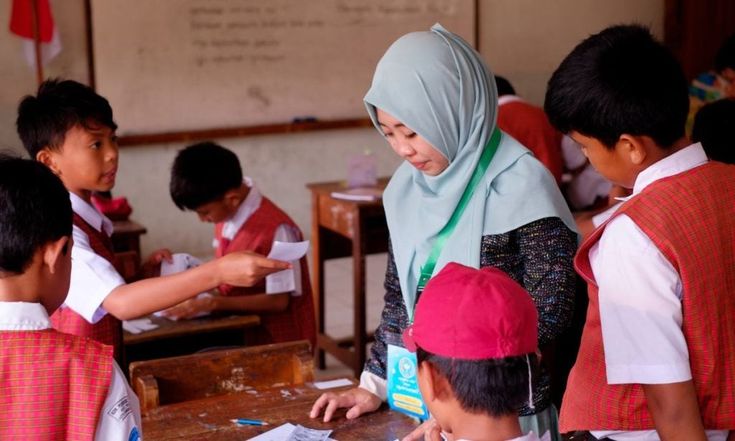 Seorang guru sedang mengajar siswanya di kelas.