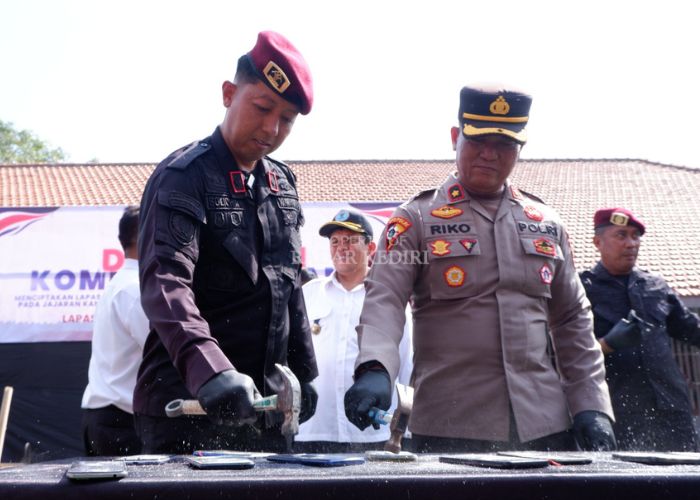 HANCURKAN: Kepala Lapas Kelas II A Kediri Solichin memusnahkan HP sitaan dari warga binaan dengan cara dipalu, kemarin.