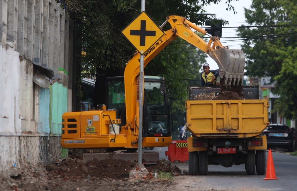 Pekerja membersihkan sisa material dan menormalisasi drainase Jalan Patiunus Kota Kediri.