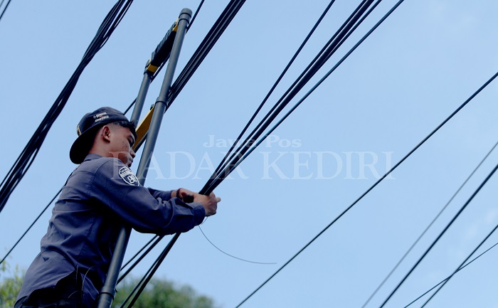 Pekerja merapikan kabel fiber optic di Jl KDP Slamet, Kota Kediri. Dalam waktu dekat pemkot berencana mencabut puluhan tiang kabel yang memperburuk wajah Kota Kediri.