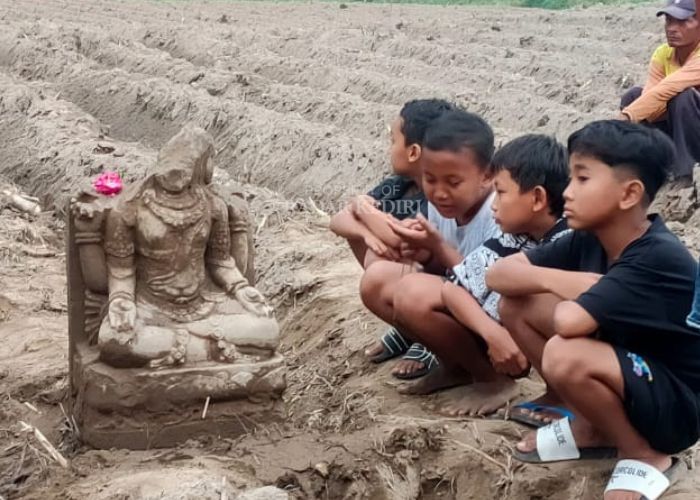 Anak-anak melihat arca yang baru saja ditemukan di Dusun Tondowongso, Desa Gayam, Kecamatan Gurah pada Jumat siang (20/6).