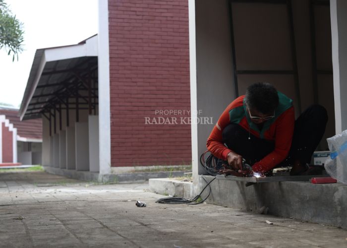 FOKUS: Salah seorang pedagang sedang mengelas pintu di lapak area PKL Kawasan Simpang Lima Gumul (SLG) Kabupaten Kediri, kemarin.