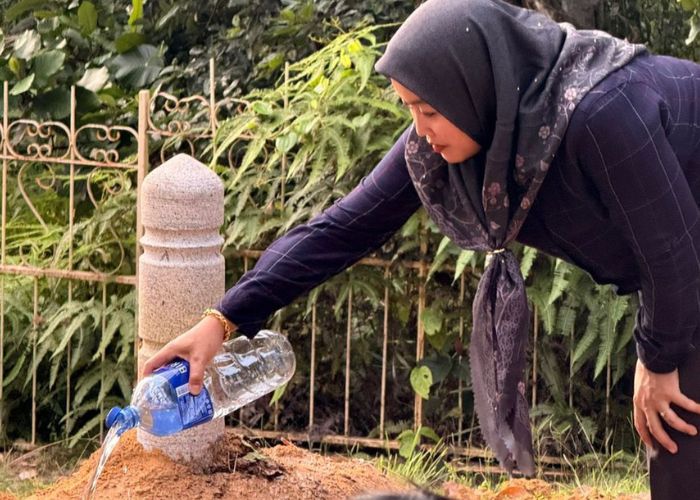 DIMAKAMKAN: Seorang warga menyiram makam di Brunei.