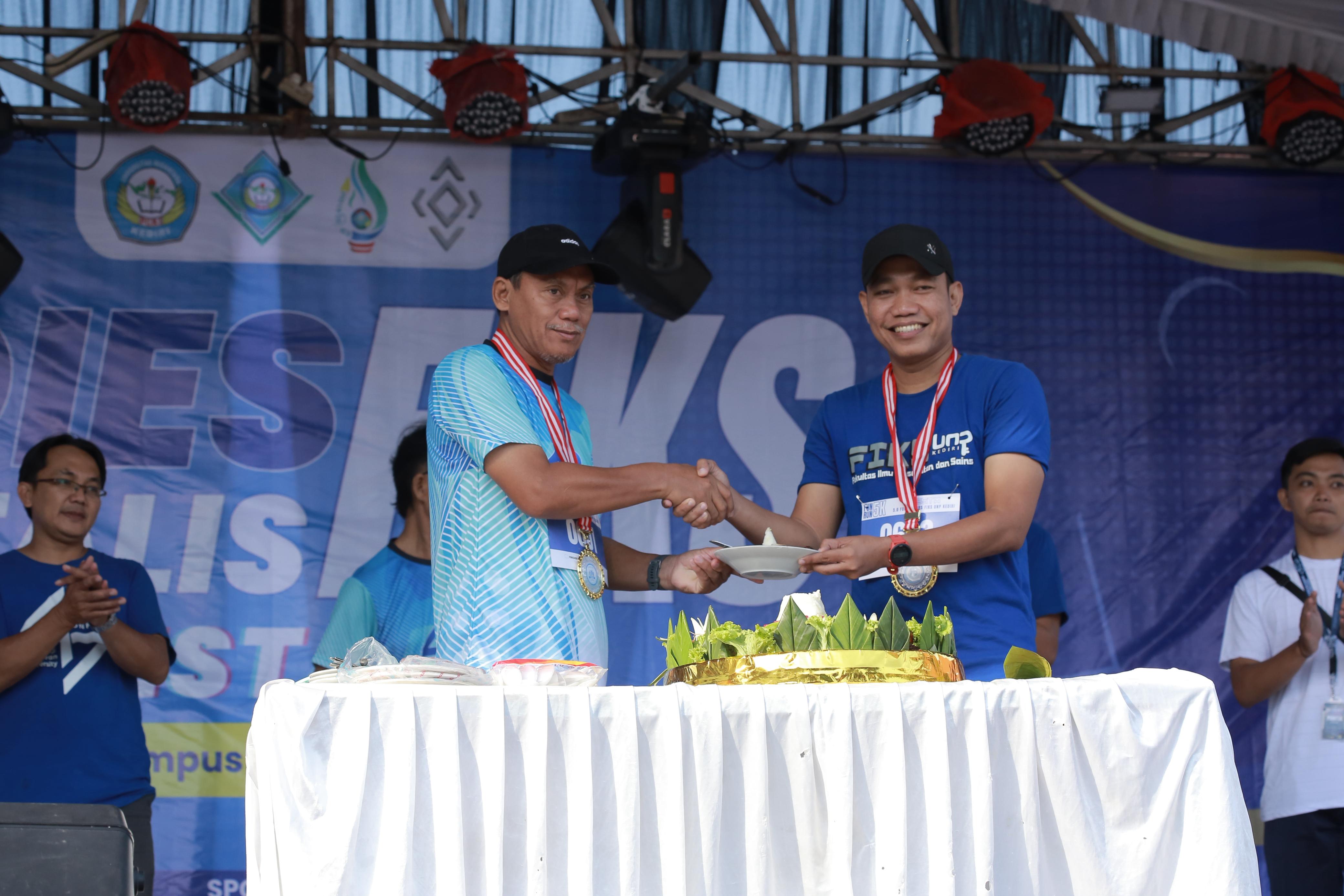 Rektor UNP Kediri Dr. Zainal Afandi, M.Pd. memberikan irisan tumpeng kepada Dekan UNP Dr. Nur Ahmad Muharram, M.Or.