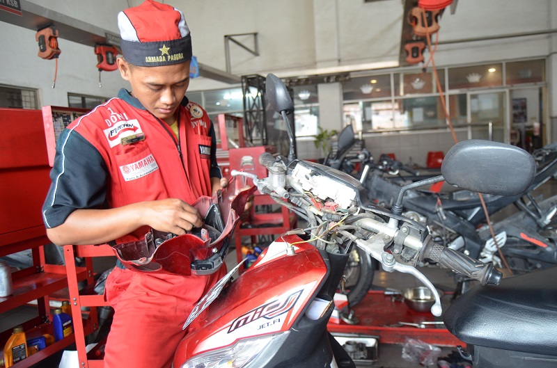 Petugas bengkel sedang melakukan pengecekan pada bagian lampu