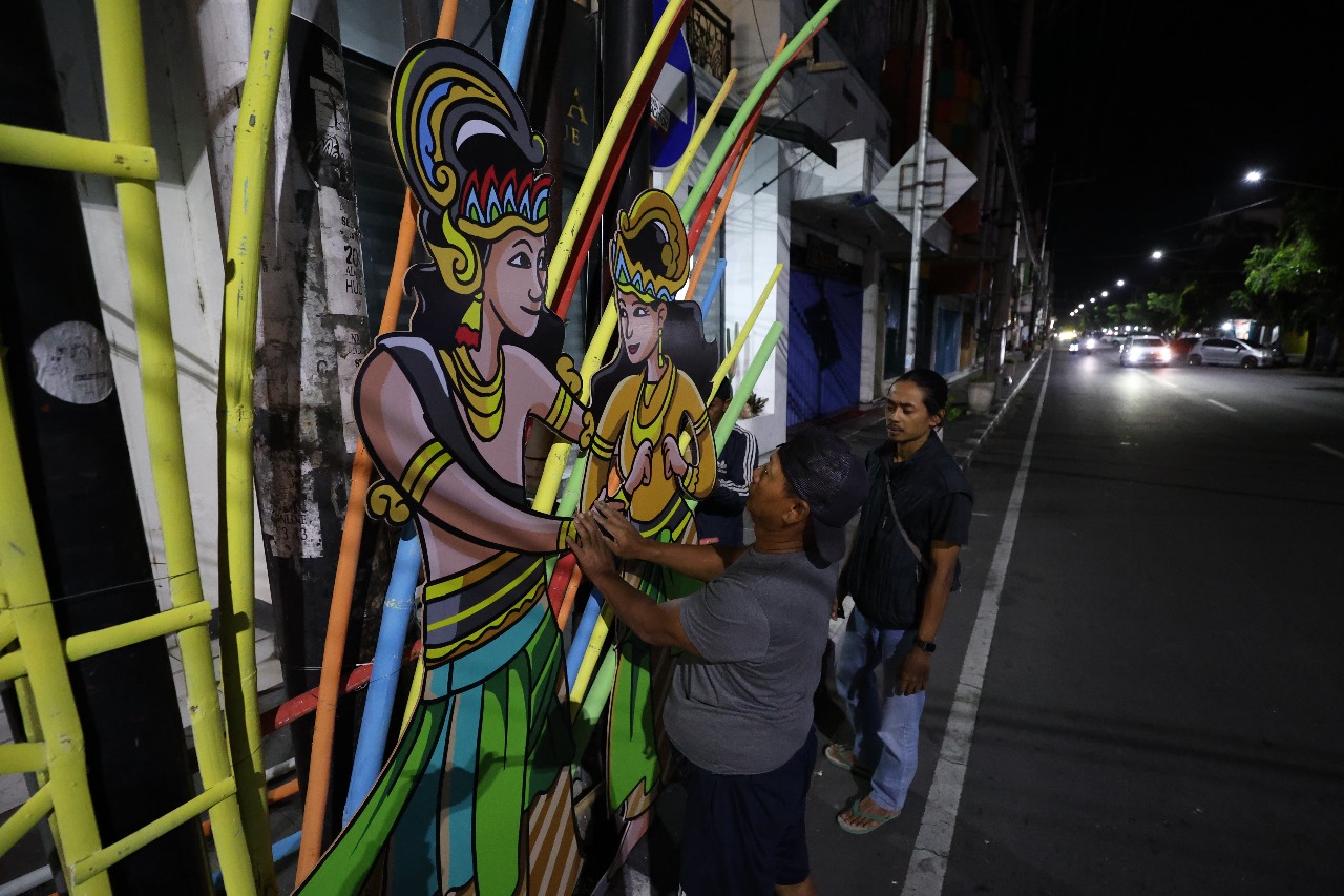 Pekerja memasang lukisan karya ilustrator Kediri yang menggambarkan kisah Raden Panji dan Sekartaji, di trotoar Jalan Dhoho Rabu malam (9/7).