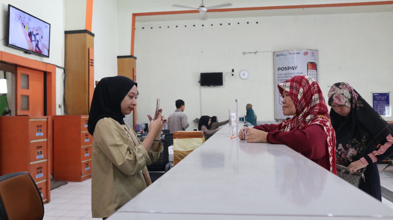 Staf Kantor Pos Besar Kediri melayani penerima manfaat BSU yang mencairkan uang bantuan kemarin (10/7).