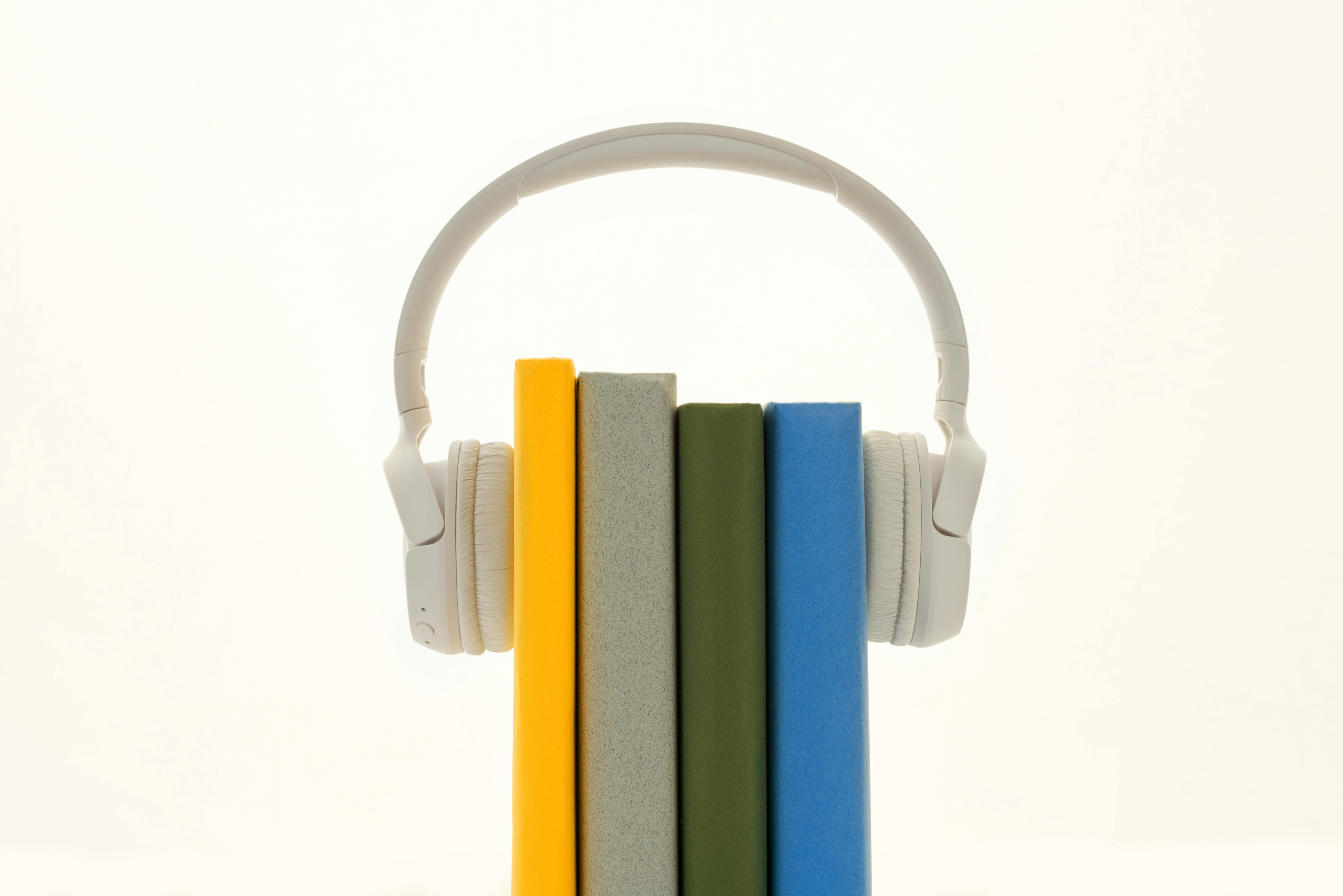 Ilustrasi - Audiobook dengan Gambaran Beberapa Buku Di Antara Headphone. Sound On/Pexels.