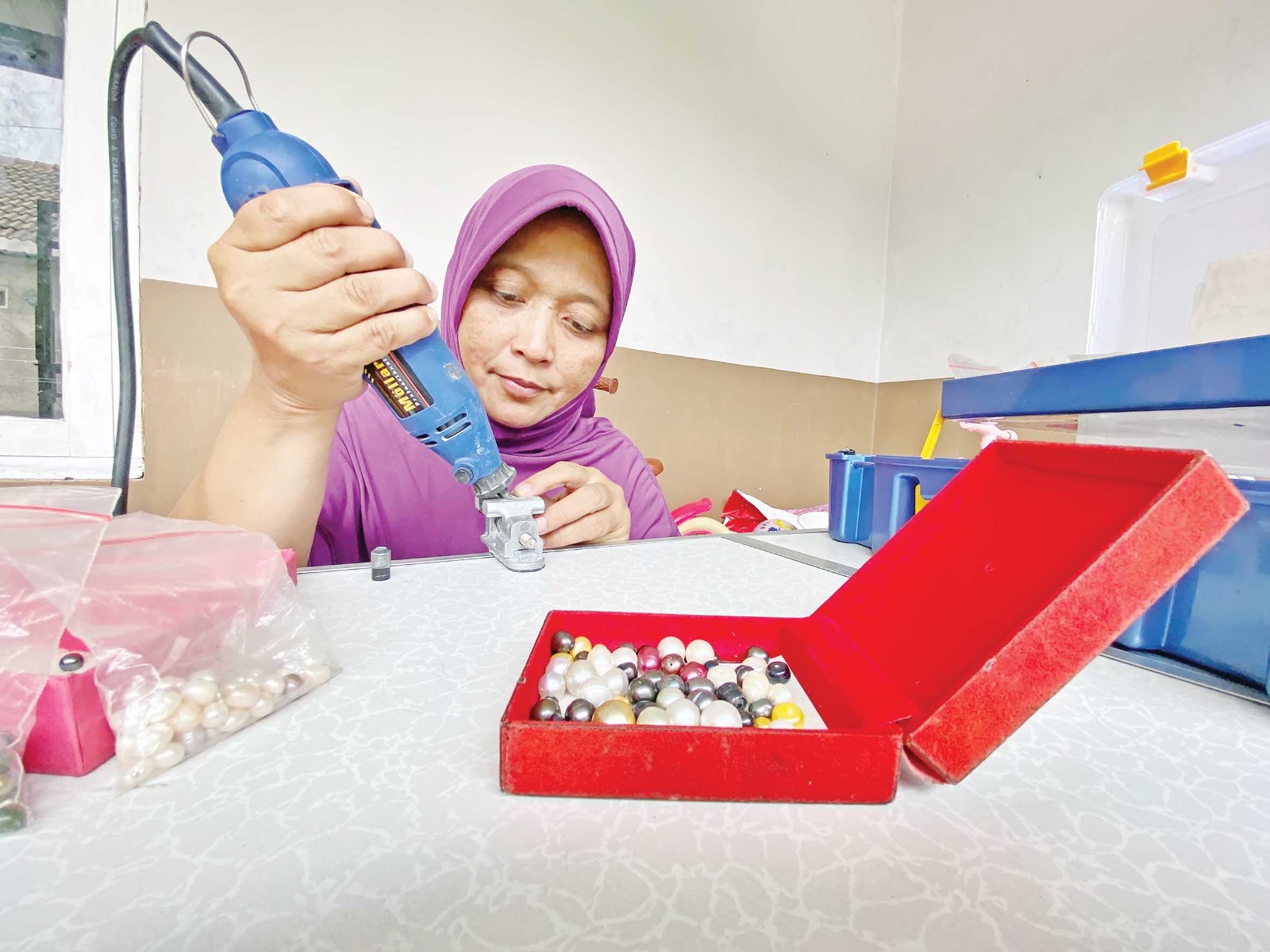 Nike memproses butiran mutiara menjadi perhiasan sesuai permintaan pemesan, di rumahnya di Desa Sambiresik, Kecamatan Gampengrejo, Kabupaten Kediri.