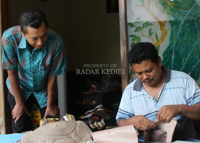 Nur Kholis mereparasi sepatu di rumahnya.