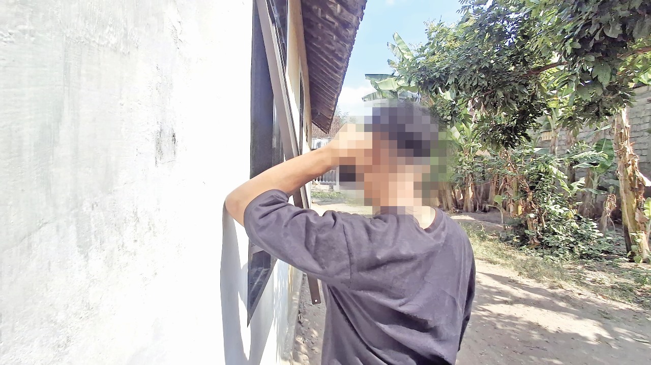 TERSAMAR: Seorang pembeli miras menunggu di depan jendela rumah penjual miras di Kecamatan Kandat.