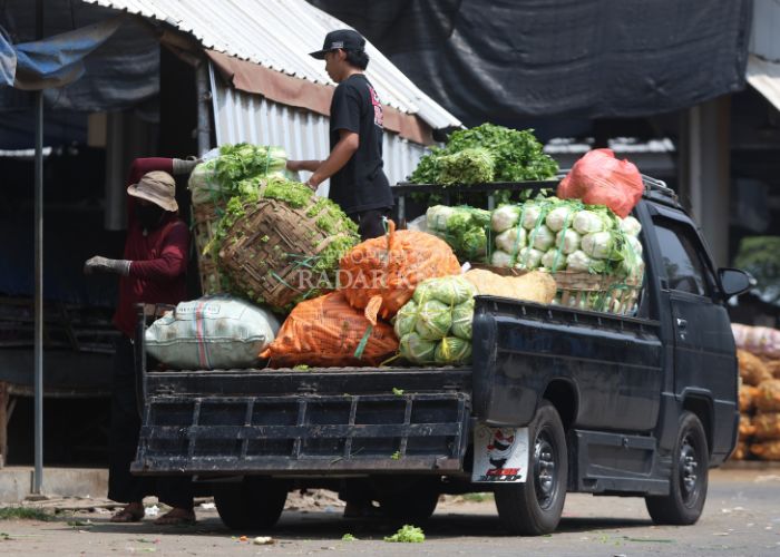 KERJA KERAS: Kuli panggul mengangkat karung sayuran di Pasar Induk Pare. Pemkab menegaskan tidak ada kenaikan retribusi melainkan digabung antara karcis masuk dan parkir.