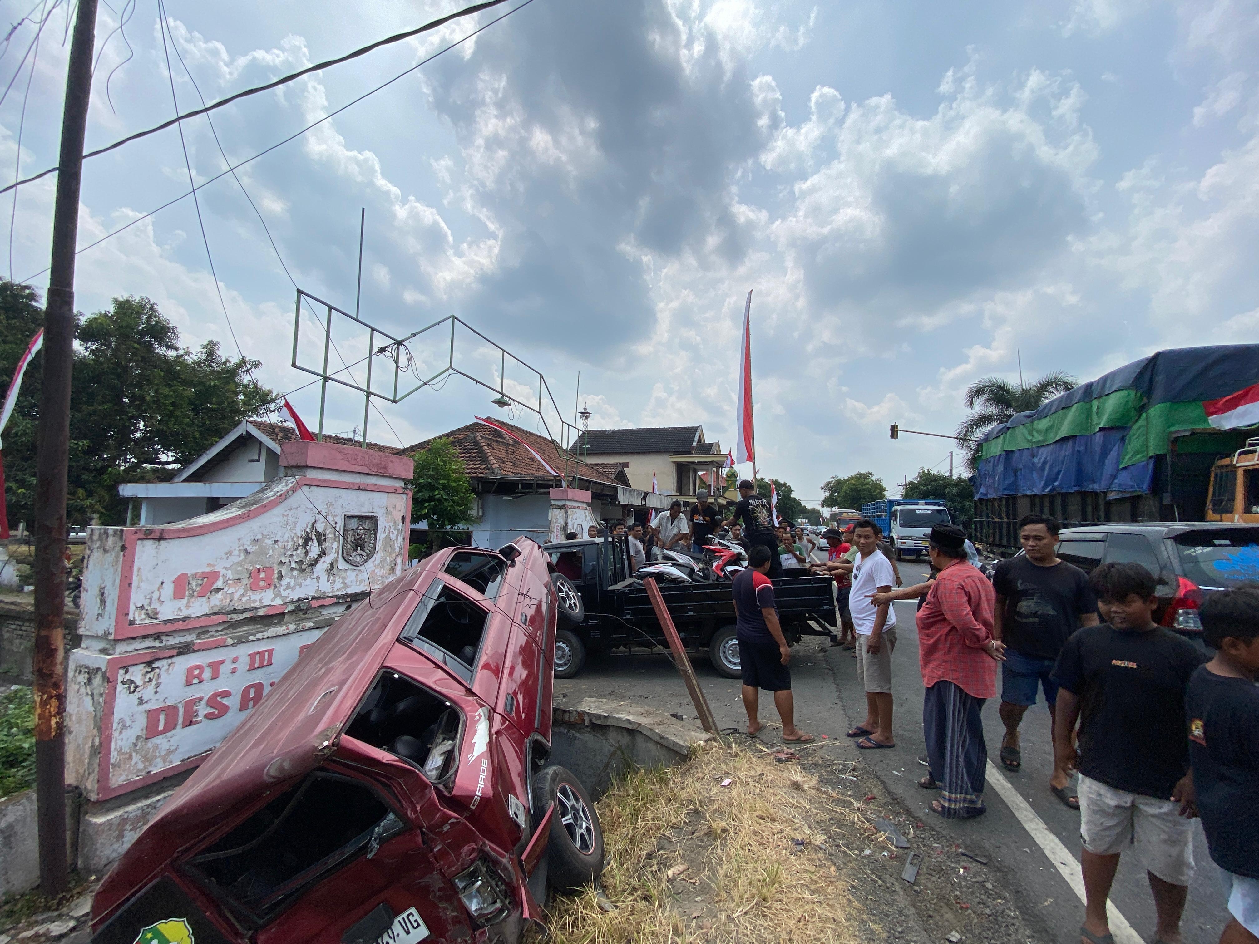Warga menyaksikan mobil Isuzu Panther yang terjerumus ke parit setelah ditabrak bus Harapan Jaya dari belakang.