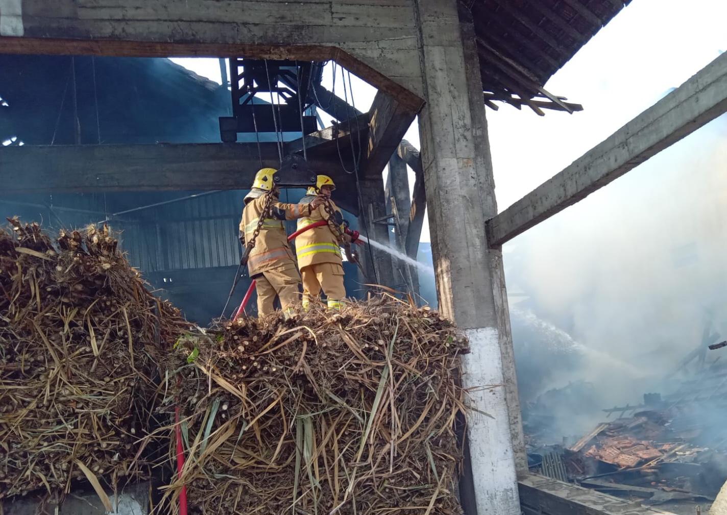 Petugas memadamkan api di pabrik gula jawa Ngletih, Kandat, Kediri.