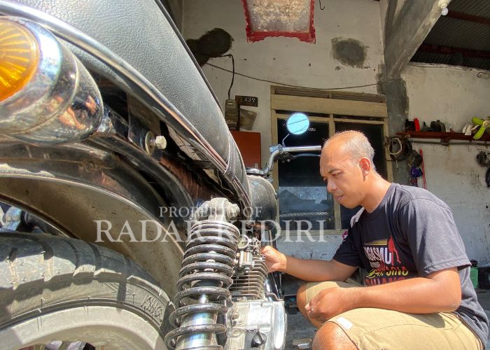 PANTANG MENYERAH: Hendrik saat service motor pelanggannya.
