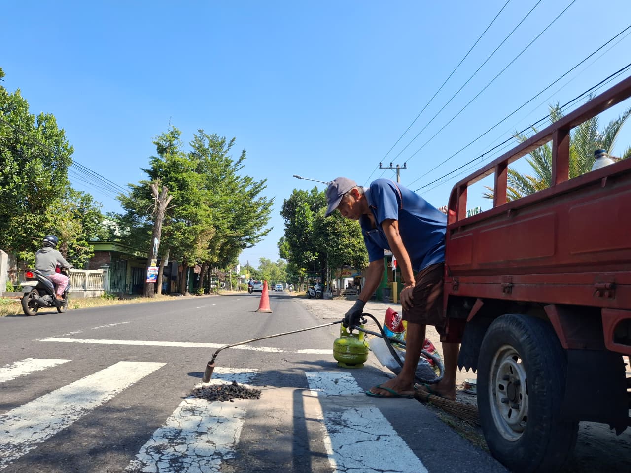 Heri Purnomo, warga Desa Langenharjo, Plemahan menambal lubang jalan menggunakan aspal bercampur batu koral. Dia tergerak jadi relawan tambal jalan setelah banyak pengendara celaka akibat jalan rusak.