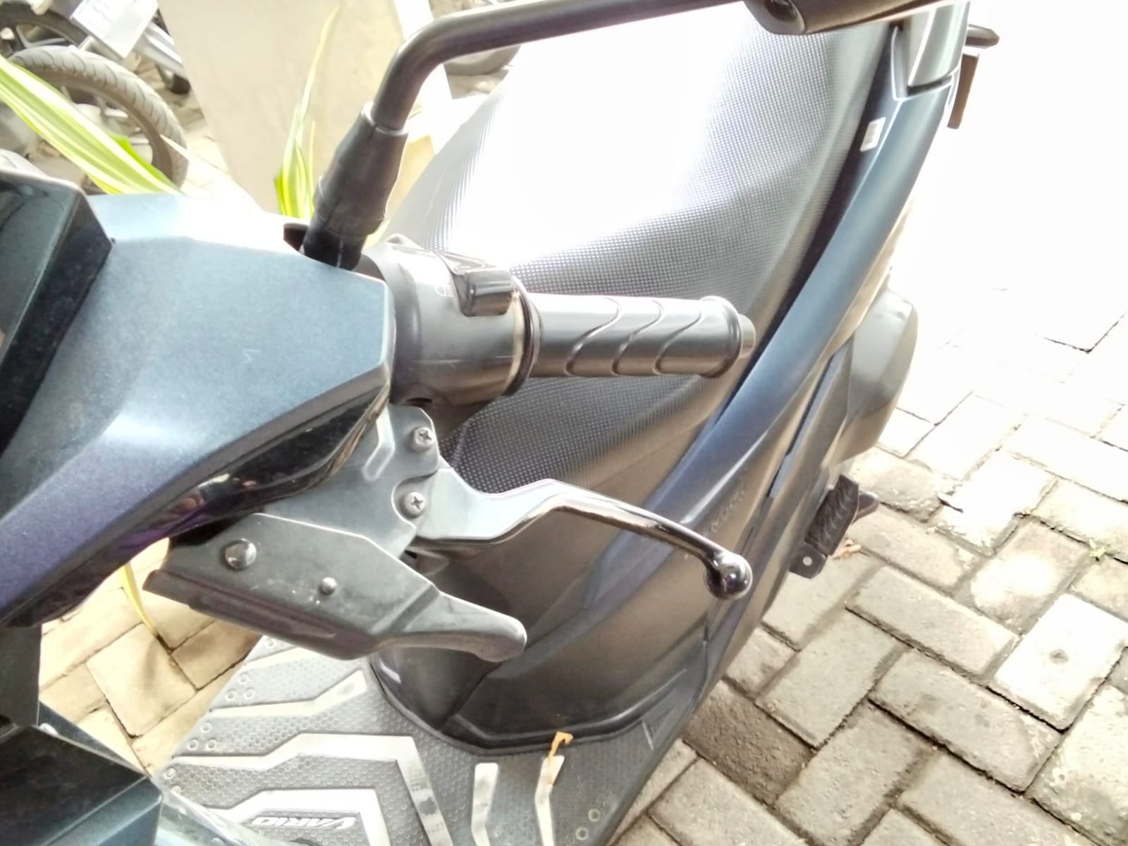 Komponen rem kiri pada setir motor matic untuk mengunci roda belakang saat parkir.