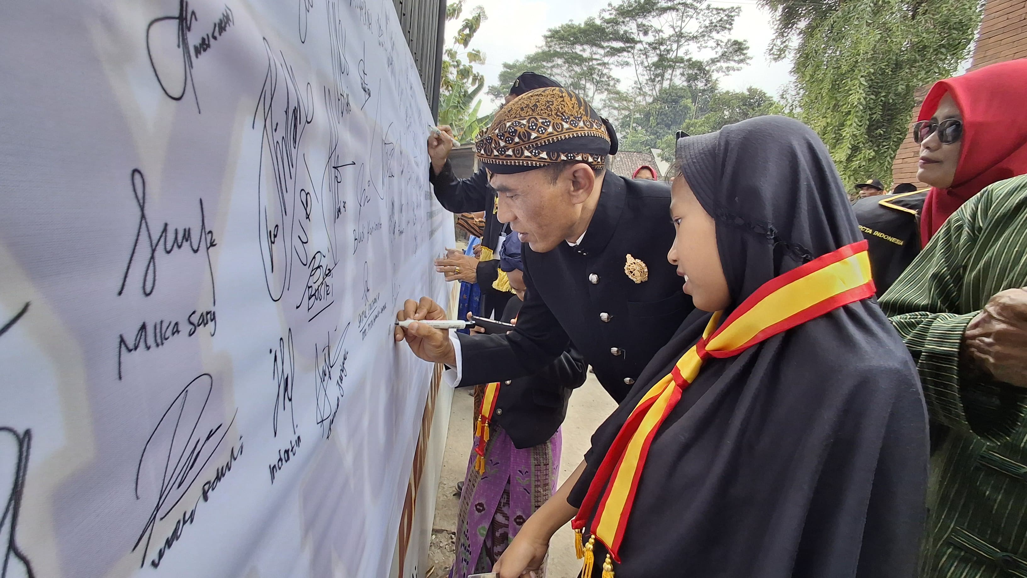 PETISI: Warga memberi dukungan dengan membubuhkan tanda tangan di kain putih.