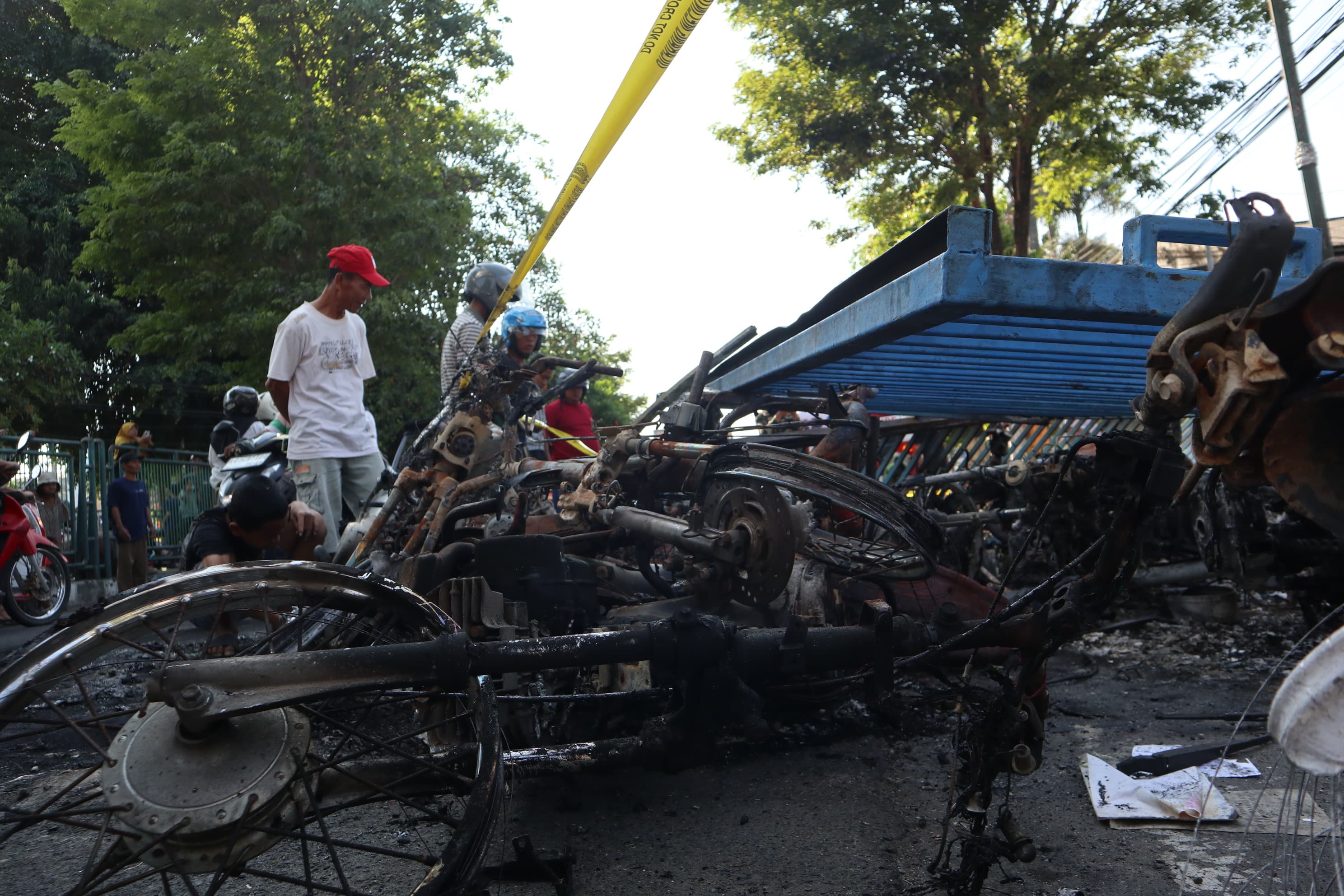 TINGGAL KERANGKA: Warga menyaksikan bangkai kendaraan yang terbakar setelah aksi tadi malam.