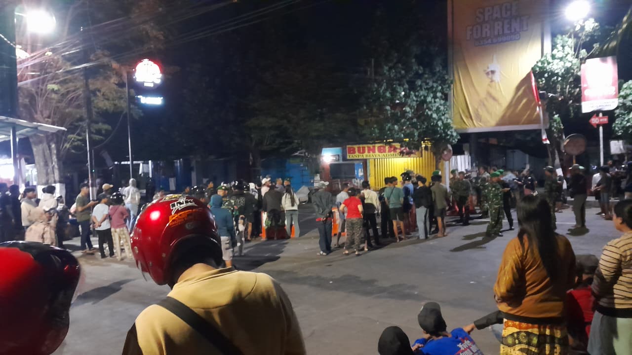 TEGANG: Warga Pare ikut menyaksikan pengamanan aksi demo yang menyasar Polres Kediri.