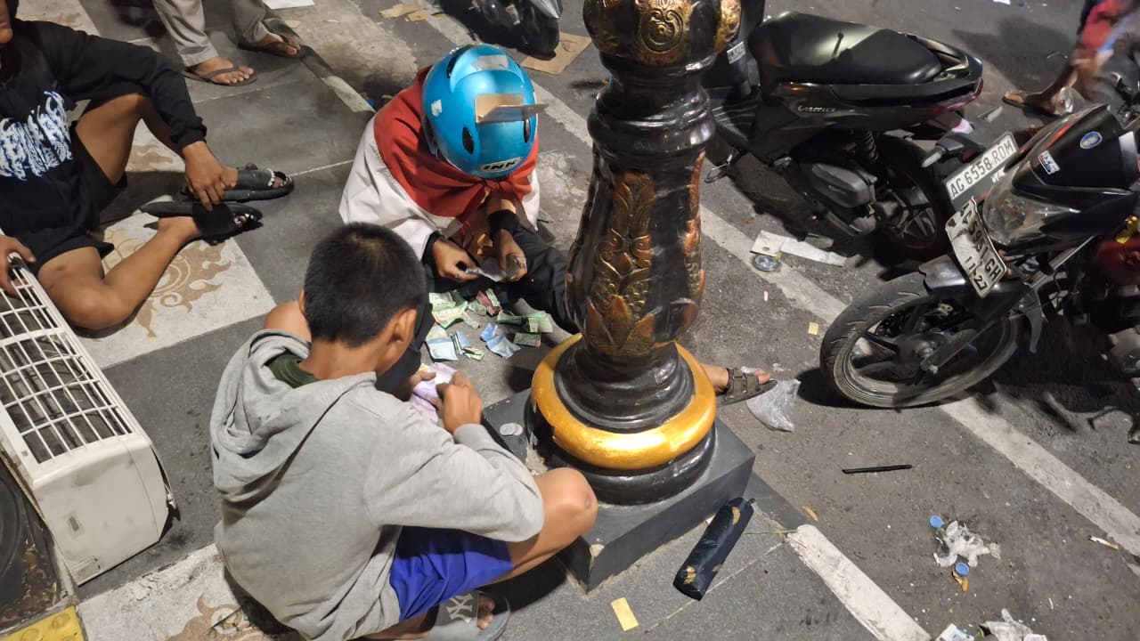 JARAH KOTAK AMAL: Dua pelajar menghitung uang  yang dijarah dari gedung DPRD Kabupaten Kediri.
