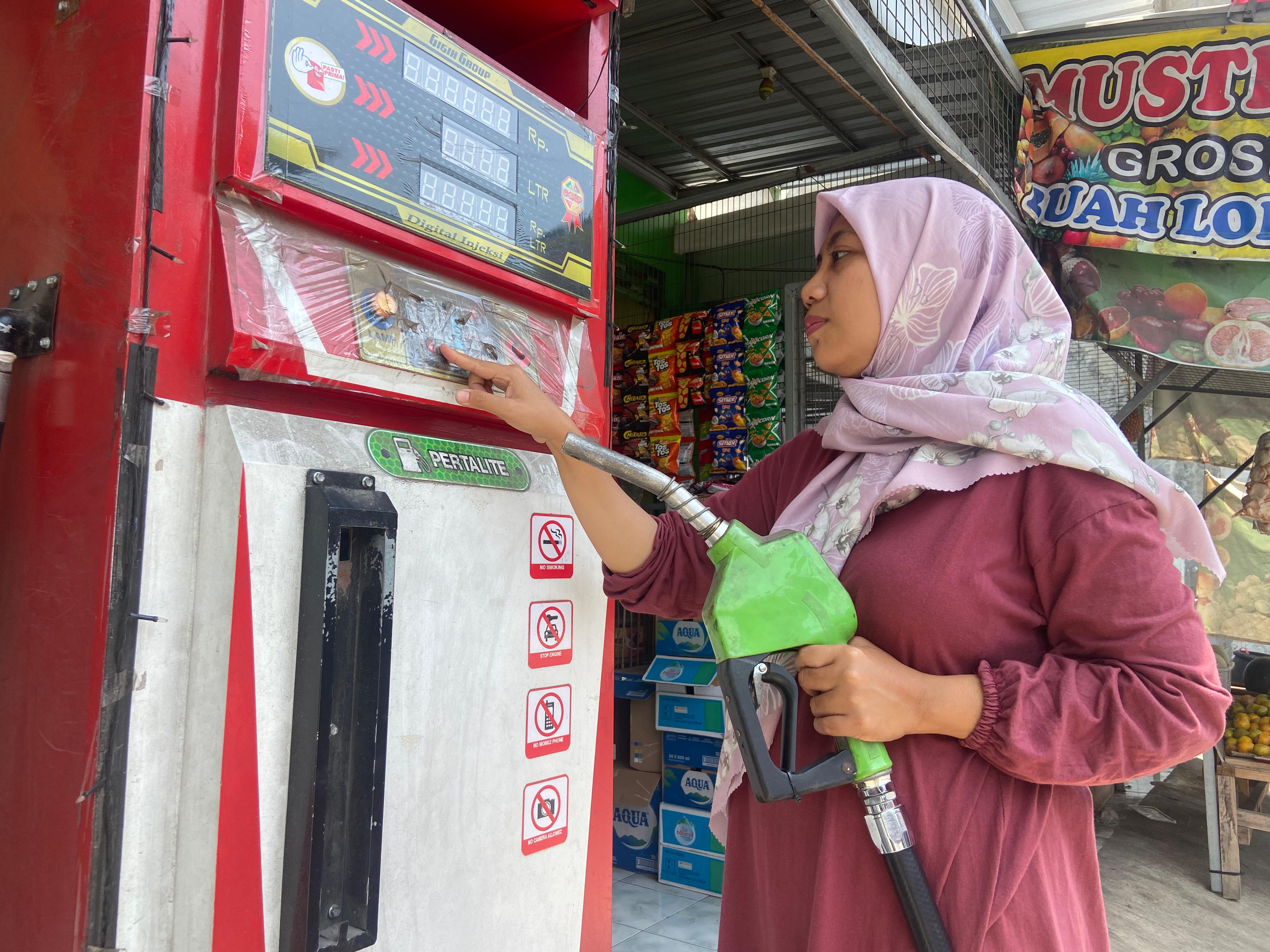 MEMBLUDAK: Pemilik pom mini di Jongbiru Kediri mengisi BBM untuk konsumennya.