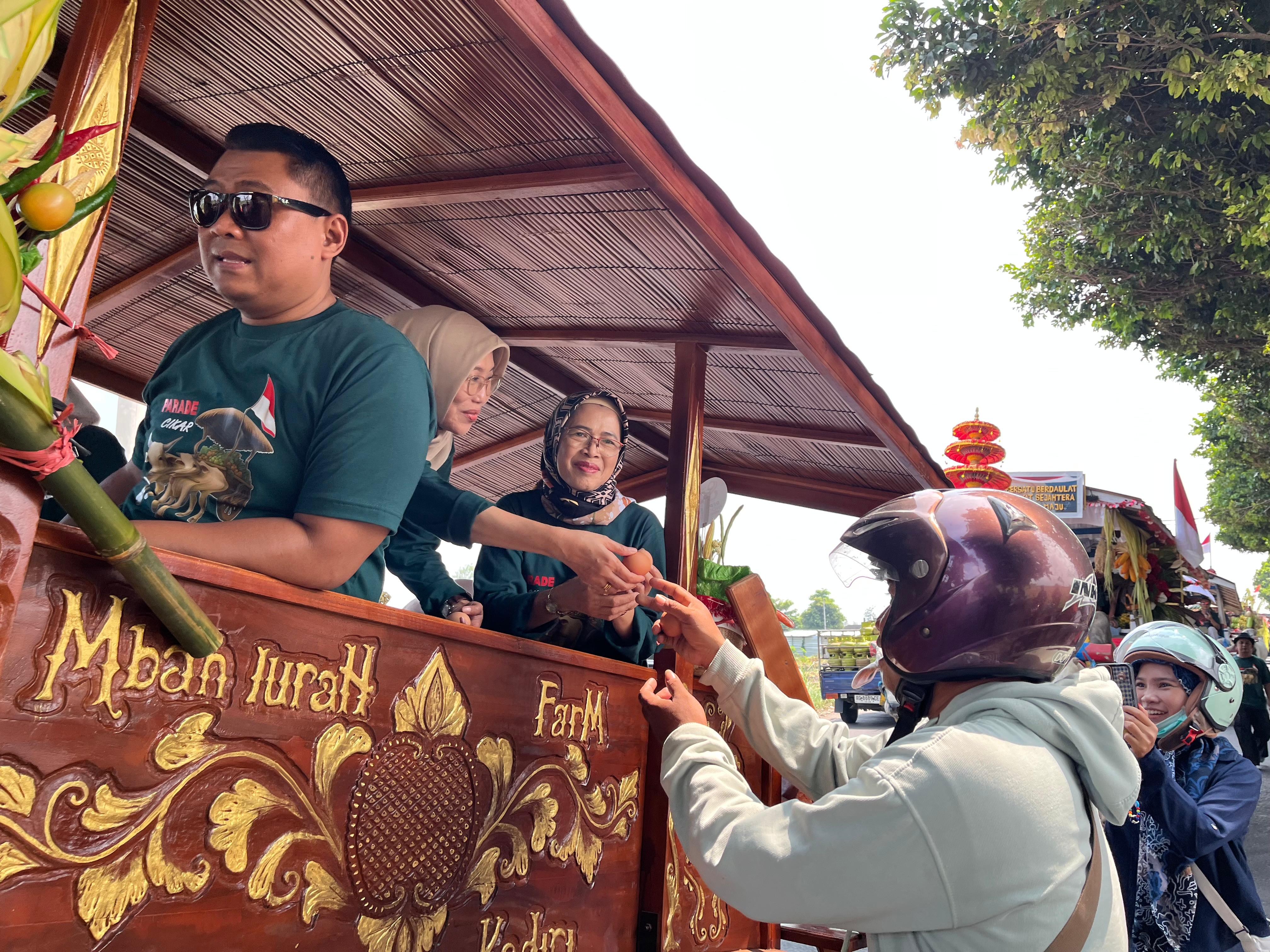 Plt Kepala DKPP drh. Tutik Purwaningsih membagikan telur rebus kepada warga sekitar yang menonton pawai.