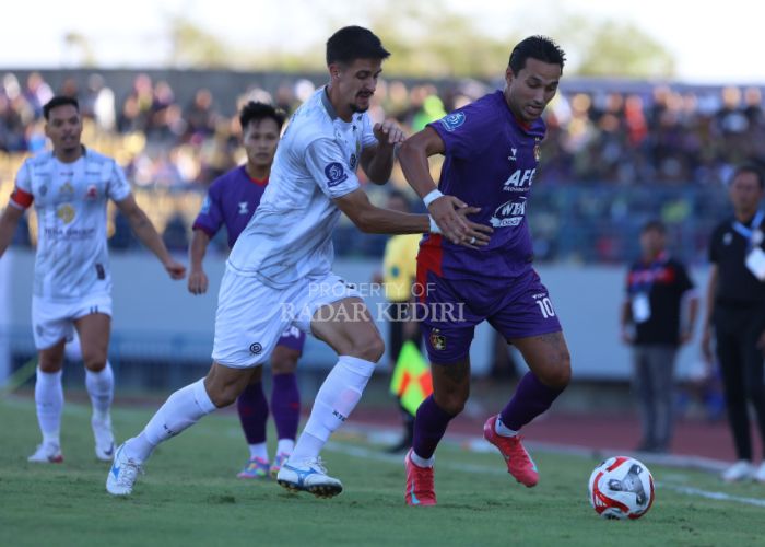Ezra Walian berduel dengan pemain Madura United FC.