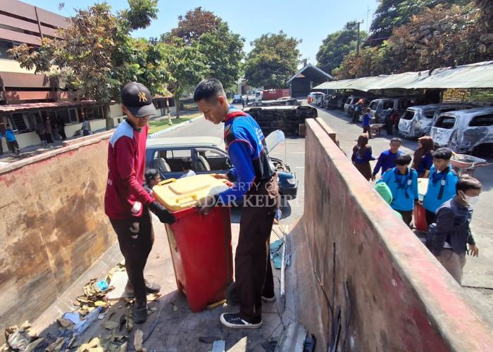 Anggota Pramuka dan relawan turut membantu membersihkan sampah sisa kerusuhan di Kantor Pemkab Kediri.