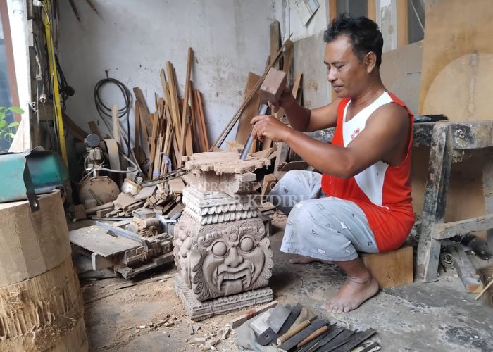 Sujoko membuat ukiran untuk sangkar burung.