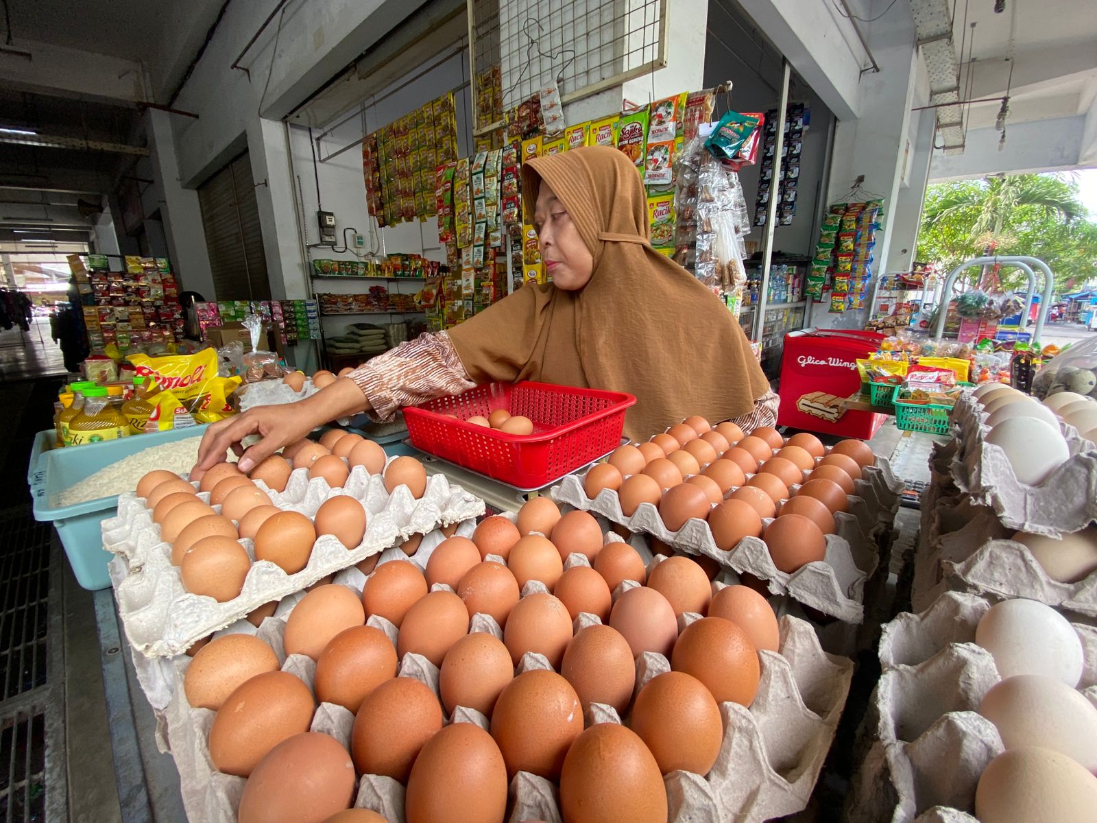 NAIK: Pedagang kelontomg sedang merapikan telur ayam.