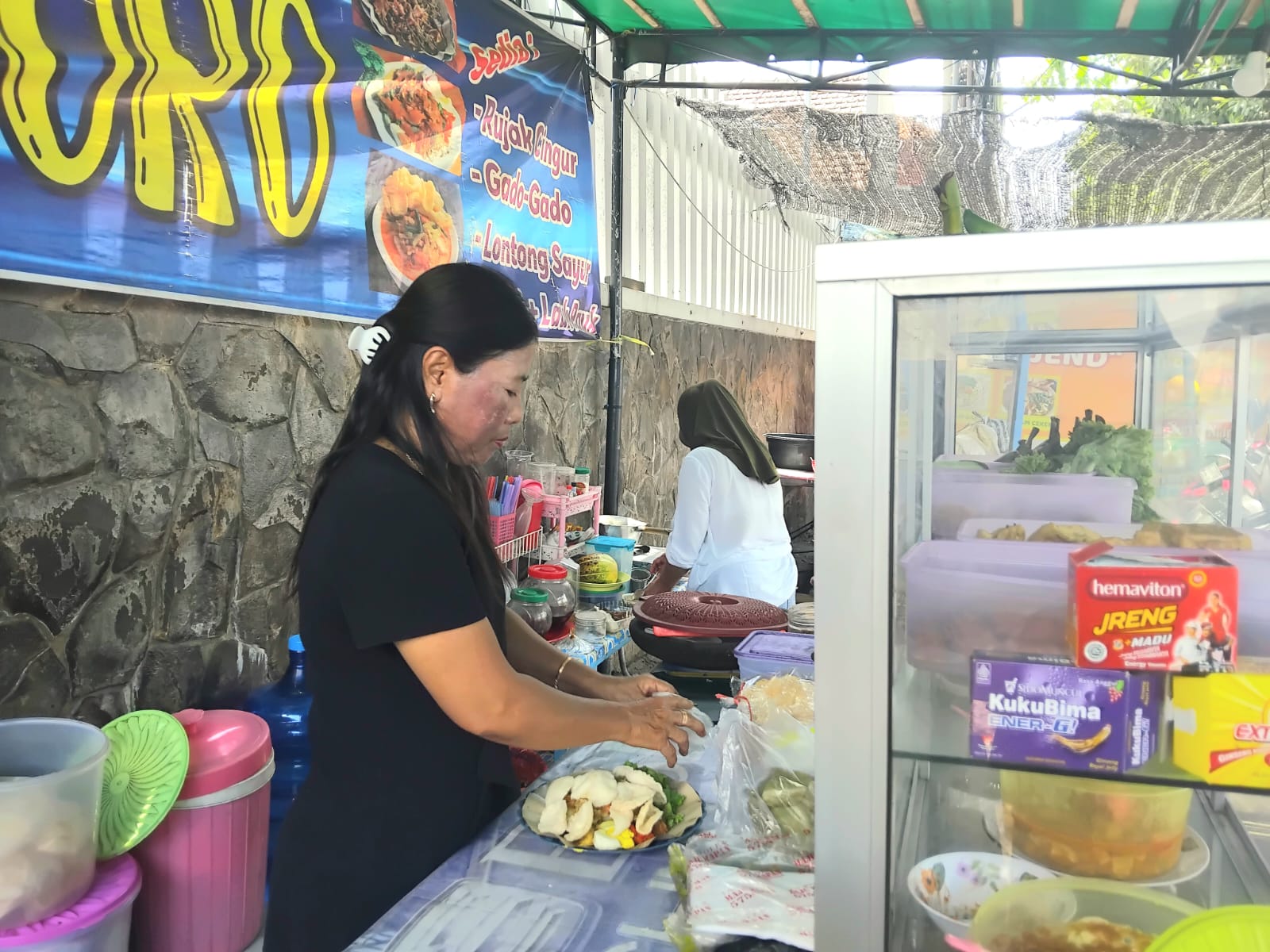 Penjual gado-gado menyajikan pesanan konsumen.