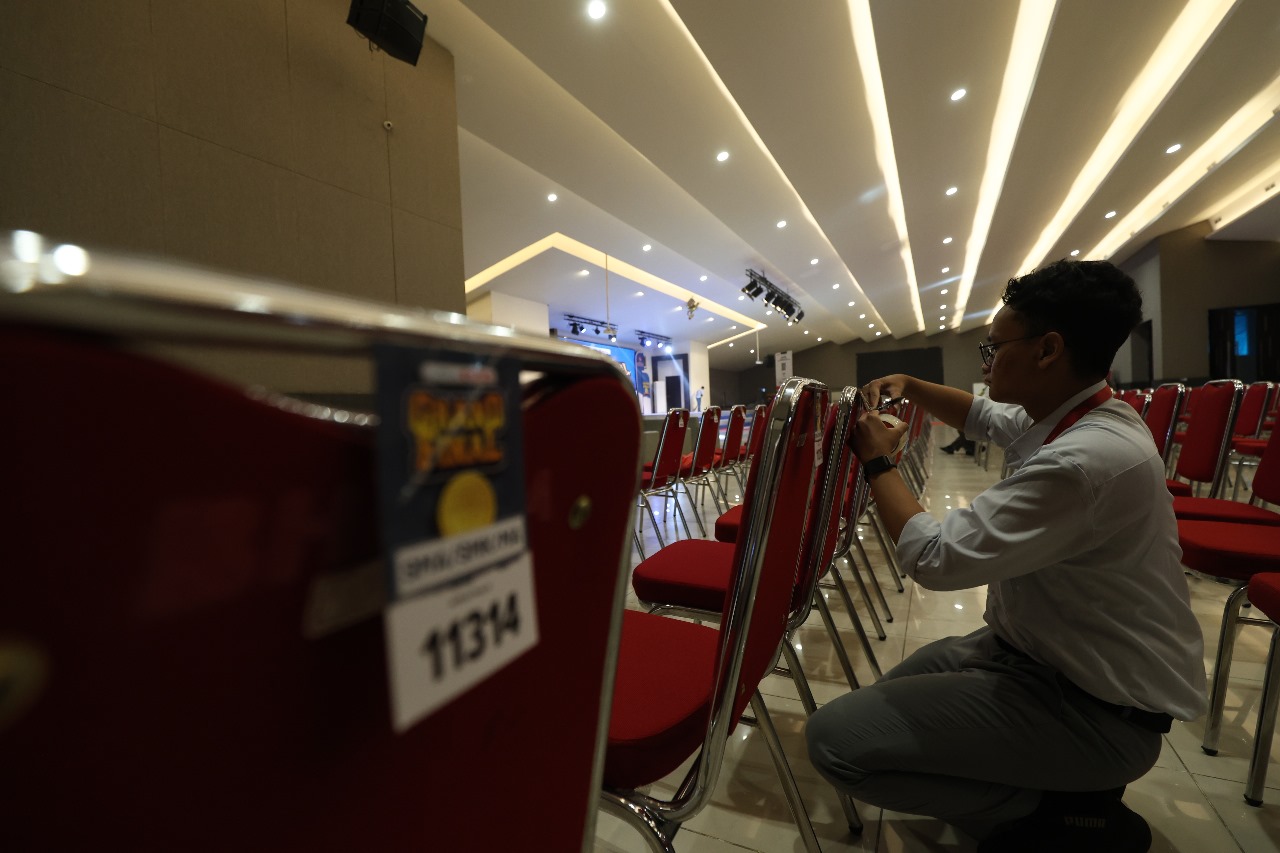 Panitia menempel nomor peserta di ratusan kursi tempat final Kompetisi Kompetensi Akademik 2025 di lantai 4 Graha IIK Bhakti Wiyata, Kelurahan/Kecamatan Mojoroto hari ini.