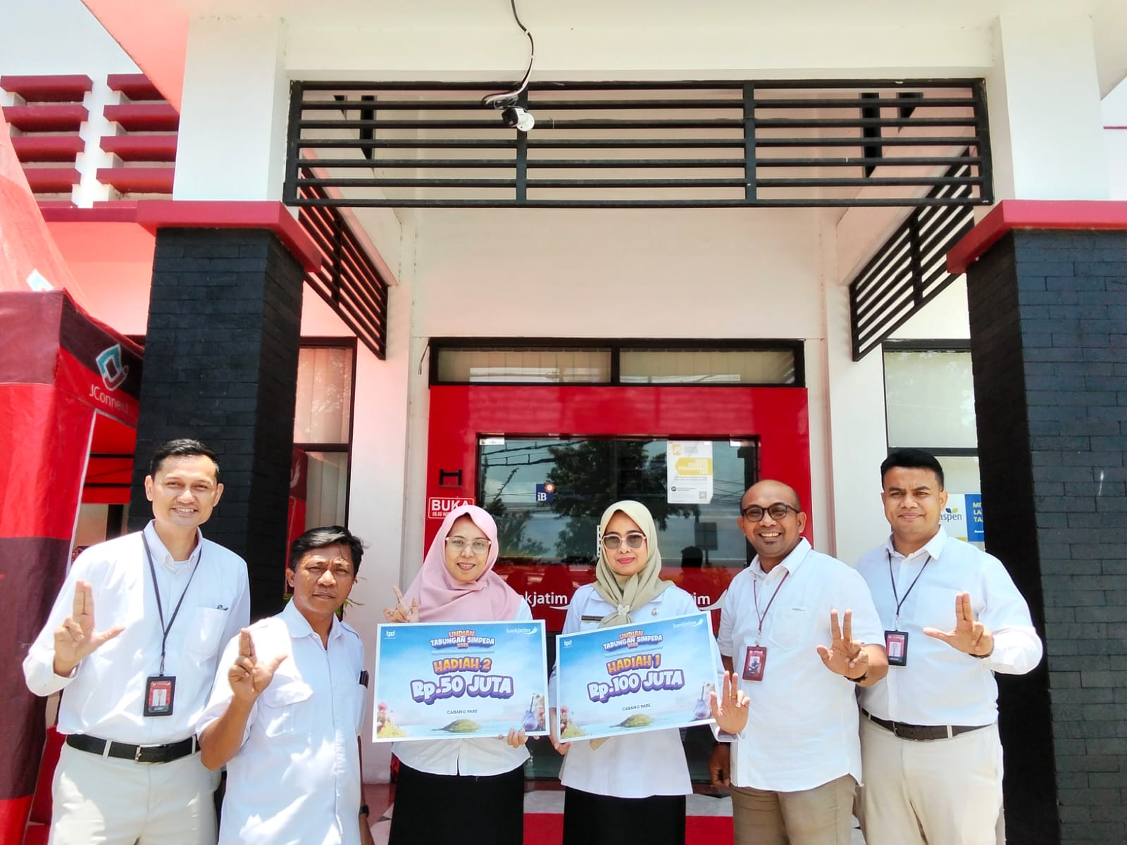 Pemimpin Cabang Bank Jatim Pare Fiki Effendy menyerahkan hadiah tabungan Simpeda kepada dua nasabah setia.