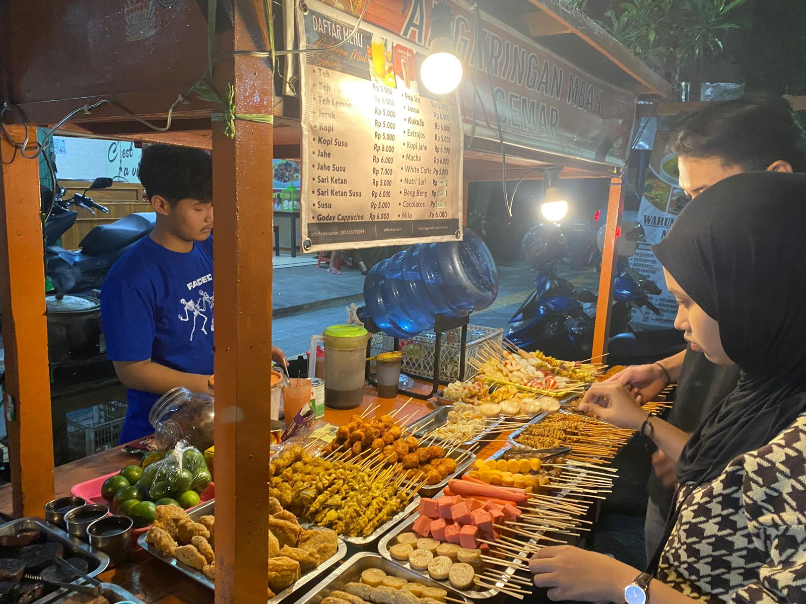 BERGELIAT: Pedagang angkringan melayani pembelinya saat buka malam hari.