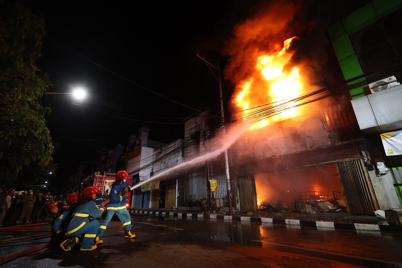 Petugas Damkar memadamkan api yang melalap Toko Mulia atau Toko Solo di Jl Dhoho pada Rabu (15/10) malam.