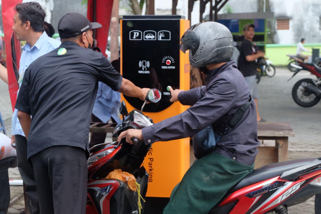 STOP KEBOCORAN: Seorang petugas mengarahkan pengunjung untuk memencet tombol ticketing.