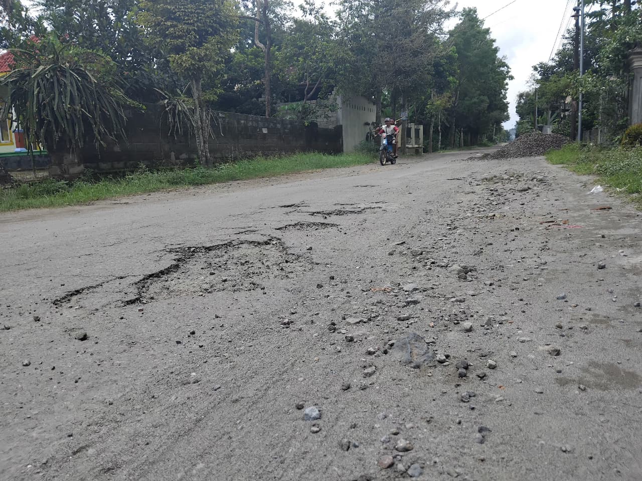 Warga melintas di jalan yang rusak parah di Desa Pojok, Kecamatan Wates