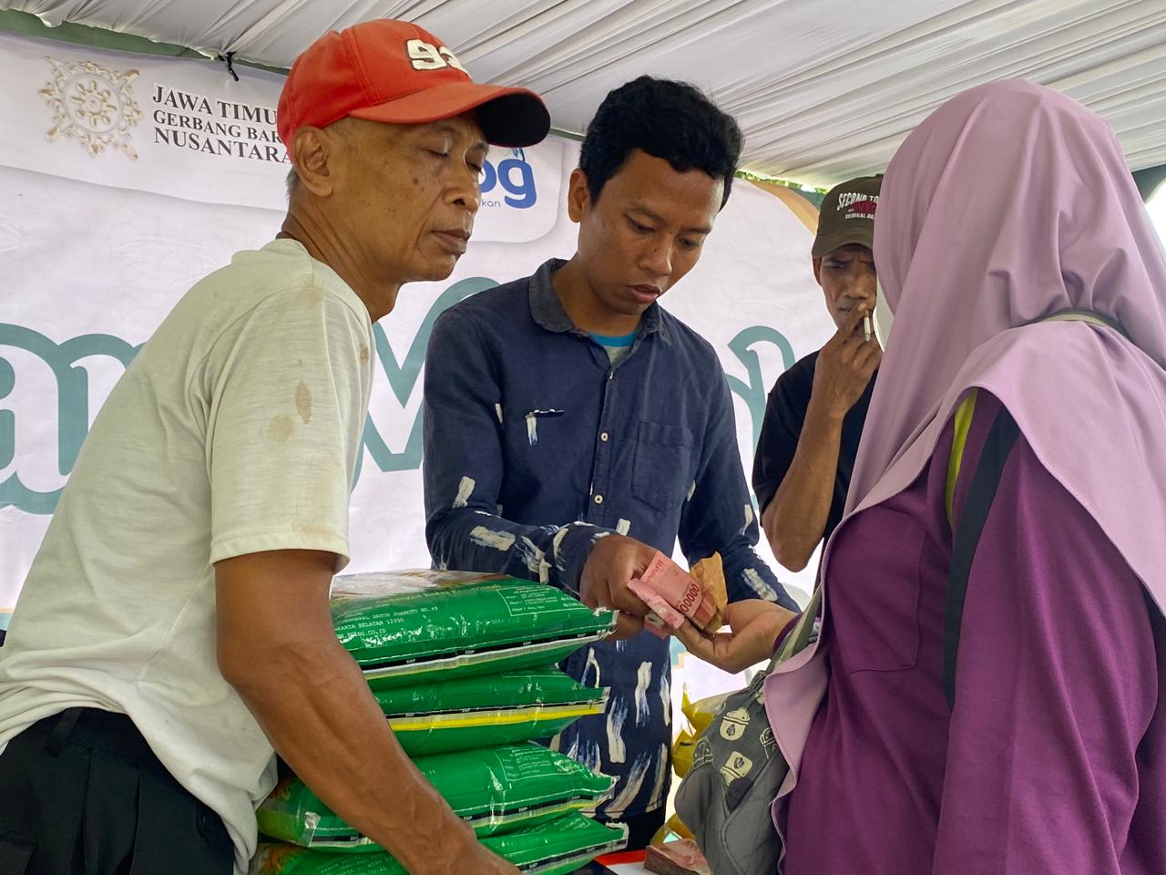 STABILKAN HARGA: Seorang warga Kota Kediri mengangkat beras yang dijual murah oleh Pemprov Jatim.
