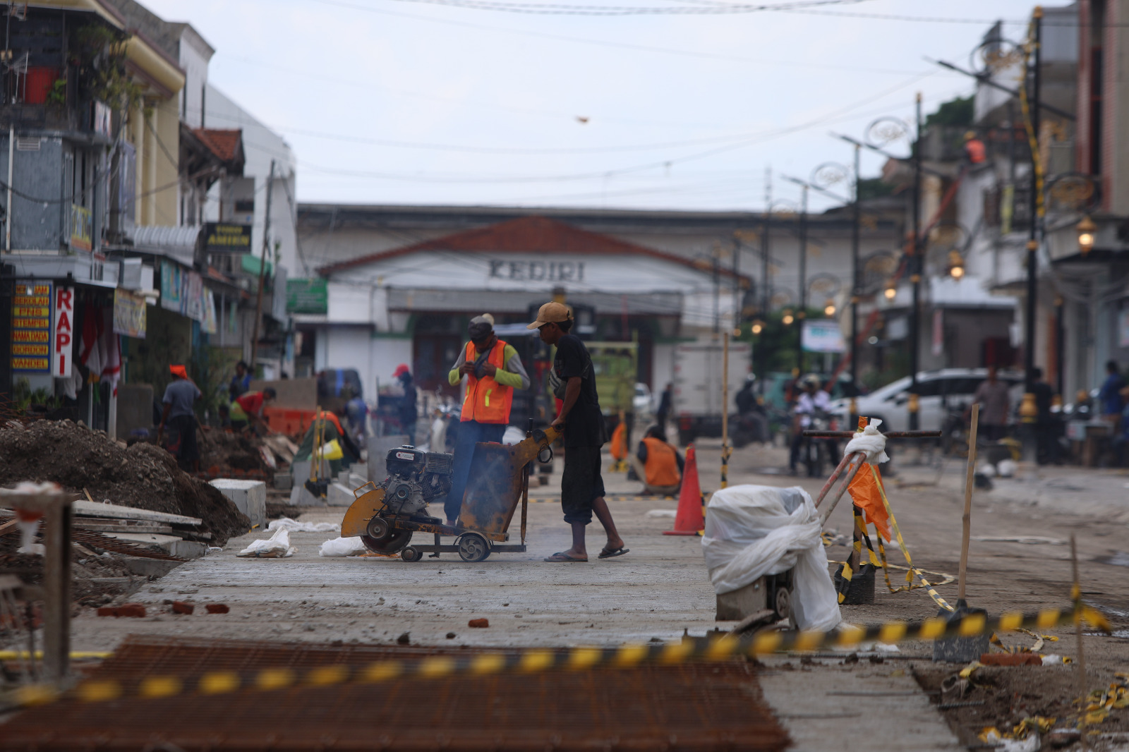 PROYEK FISIK: Dua pekerja mengerjakan jalan di Jalan Stasiun Kediri.